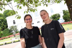 Zwei junge Frauen in schwarzen T-Shirts stehen nebeneinander vor dem Rendsburger Stadttheater und lächeln in die Kamera.